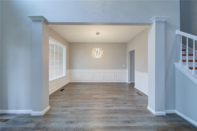 unfurnished dining area with a chandelier, stairway, visible vents, and wood finished floors
