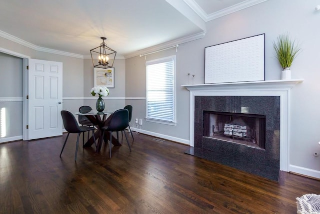 dining area with a premium fireplace, crown molding, a chandelier, and dark hardwood / wood-style flooring