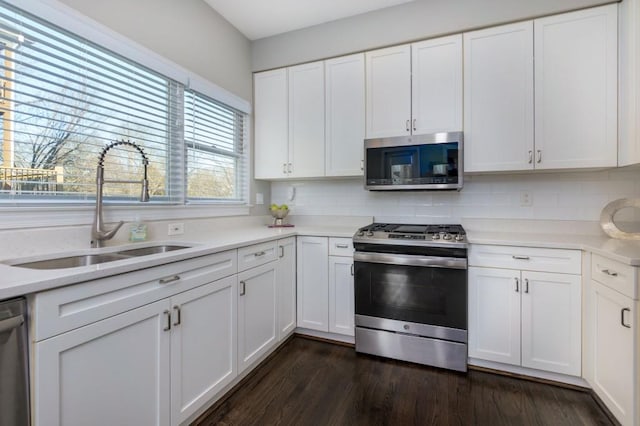 kitchen featuring appliances with stainless steel finishes, dark hardwood / wood-style flooring, sink, and white cabinets