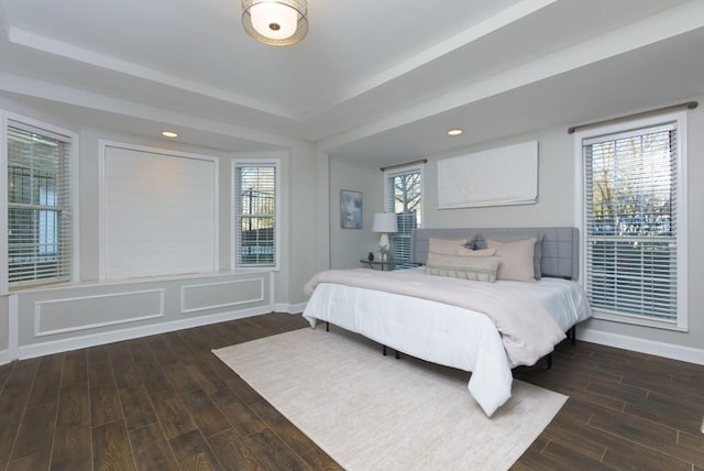 bedroom with dark hardwood / wood-style flooring and a tray ceiling