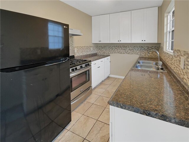 kitchen with black fridge, tasteful backsplash, stainless steel range with gas stovetop, light tile patterned floors, and sink