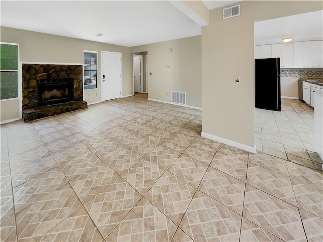 unfurnished living room featuring light tile patterned floors and a stone fireplace