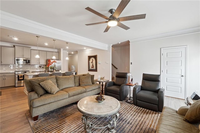 living room with crown molding, ceiling fan, and light wood-type flooring