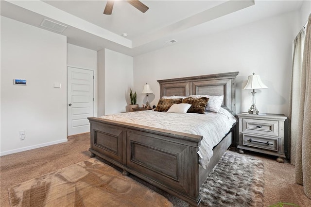 carpeted bedroom with ceiling fan and a tray ceiling