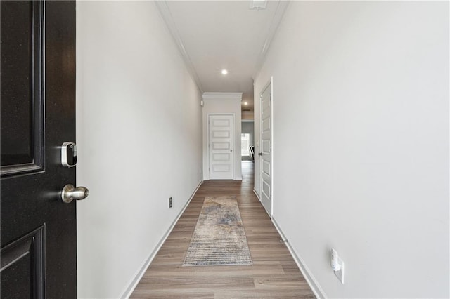 hallway with crown molding and light hardwood / wood-style flooring