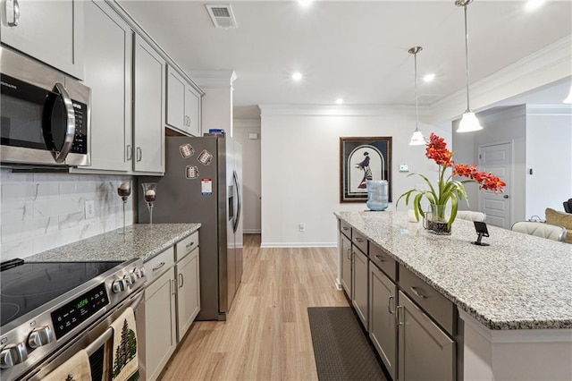 kitchen with gray cabinetry, hanging light fixtures, stainless steel appliances, a center island, and ornamental molding