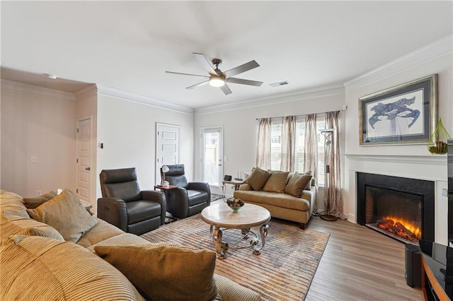 living room featuring crown molding, light hardwood / wood-style floors, and ceiling fan