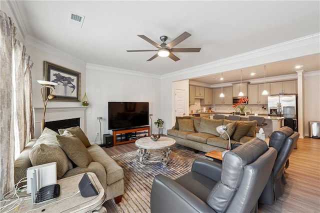 living room featuring crown molding, ceiling fan, and light wood-type flooring