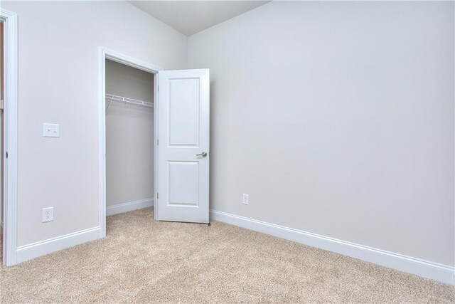 unfurnished bedroom featuring light colored carpet and a closet