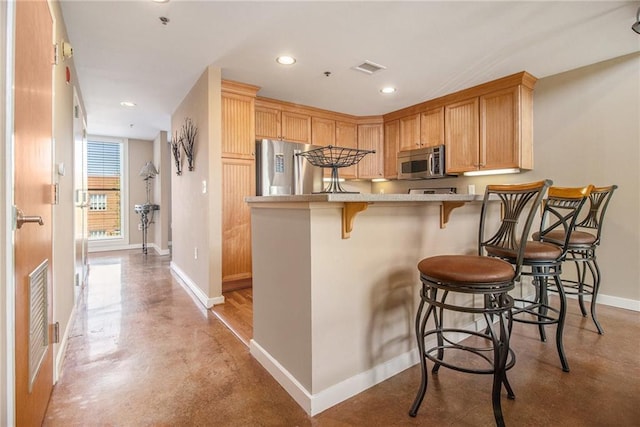 1133 Church St Unit 1, Covington, GA 30014 - kitchen with stainless steel appliances, finished concrete flooring, baseboards, a kitchen bar, and a peninsula