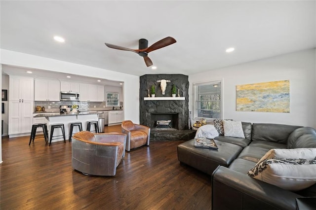 living area with dark wood-type flooring, recessed lighting, a fireplace, and a ceiling fan