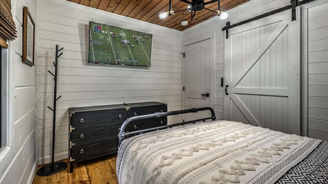 bedroom featuring a barn door, wood ceiling, and wood finished floors