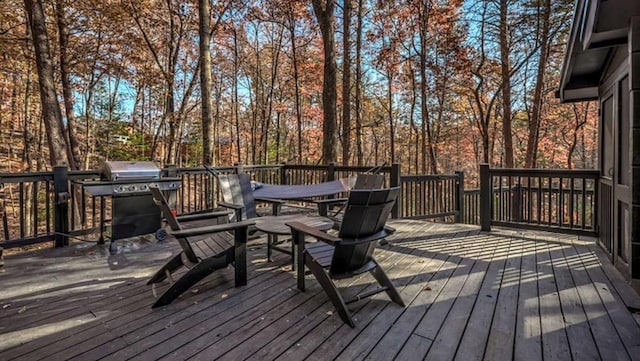 wooden terrace with outdoor dining space and grilling area