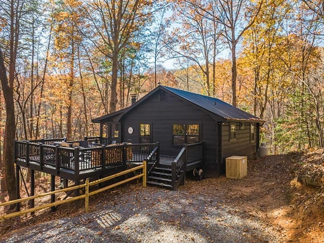 exterior space with a deck, a forest view, and metal roof