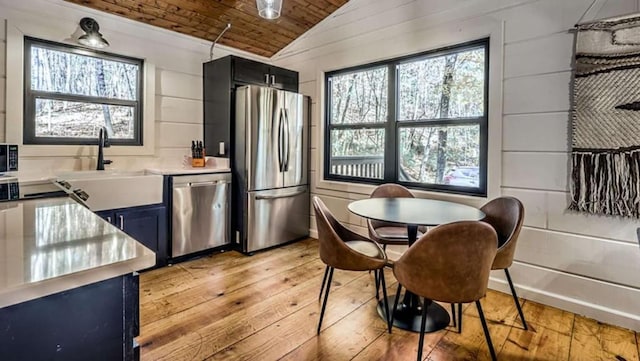 kitchen featuring light wood finished floors, wood ceiling, lofted ceiling, stainless steel appliances, and a sink