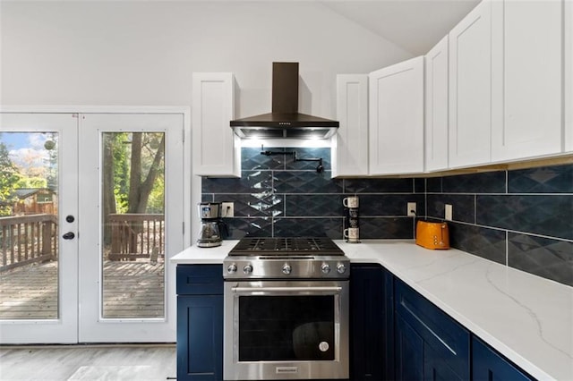 kitchen with light stone counters, high end stove, white cabinets, blue cabinets, and wall chimney exhaust hood