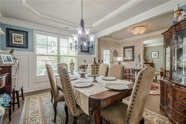 285 Turtle Rock Pl, Acworth, GA 30101 - dining space with a chandelier, a decorative wall, a wainscoted wall, crown molding, and wood finished floors