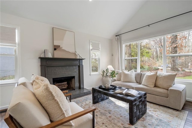 living room with lofted ceiling, a fireplace, light hardwood / wood-style flooring, and plenty of natural light