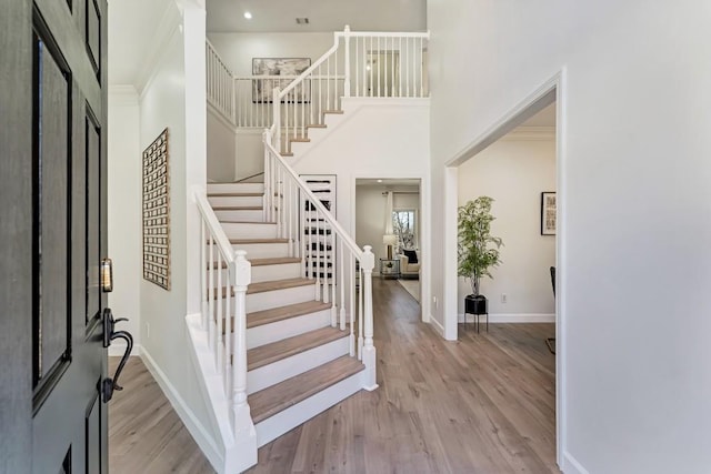 foyer entrance featuring stairway, a high ceiling, baseboards, and wood finished floors