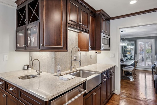 kitchen with a sink, wood finished floors, appliances with stainless steel finishes, crown molding, and light stone countertops