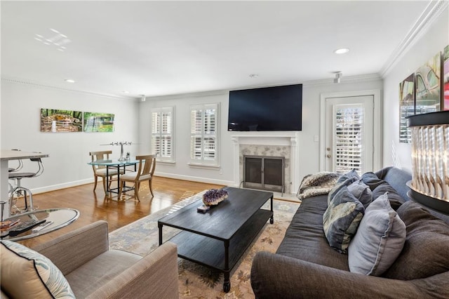 living room with baseboards, ornamental molding, recessed lighting, a fireplace, and light wood-style floors