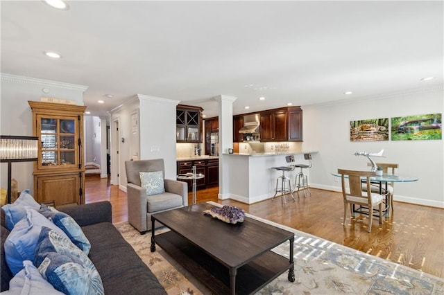 living room featuring crown molding, recessed lighting, baseboards, and light wood finished floors