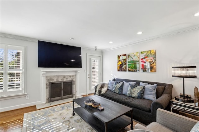 living area with ornamental molding, wood finished floors, recessed lighting, a premium fireplace, and baseboards