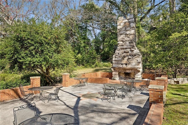 view of patio / terrace with outdoor dining area and an outdoor stone fireplace