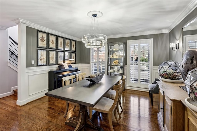 dining area with dark wood-type flooring, a wainscoted wall, ornamental molding, a notable chandelier, and a decorative wall