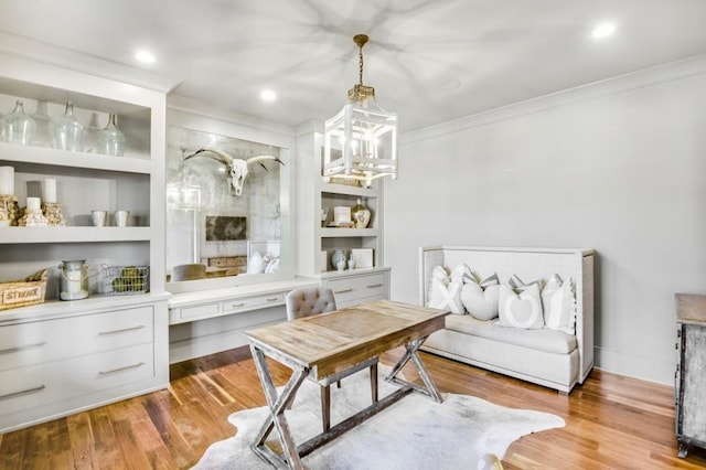 office space with a chandelier, built in features, light wood-style flooring, and crown molding