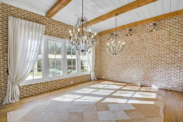 unfurnished dining area with brick wall, beamed ceiling, wood finished floors, and an inviting chandelier