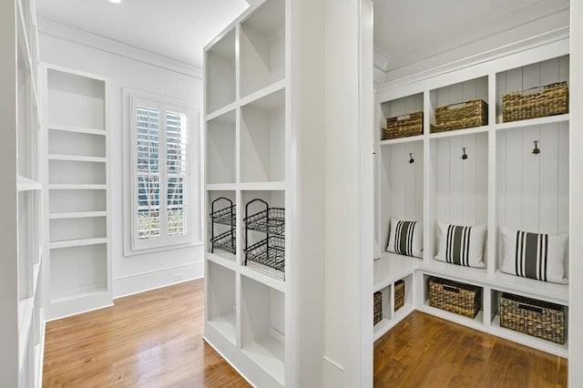 mudroom featuring crown molding, built in shelves, and wood finished floors