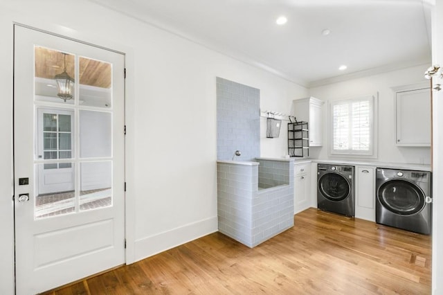 laundry room featuring light wood-type flooring, washing machine and clothes dryer, cabinet space, and crown molding