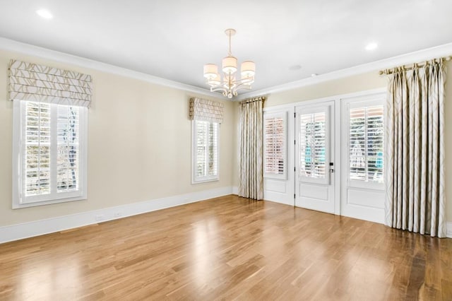 spare room featuring a chandelier, ornamental molding, wood finished floors, and baseboards