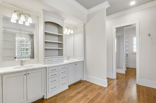 bathroom with ornamental molding, a sink, baseboards, and wood finished floors