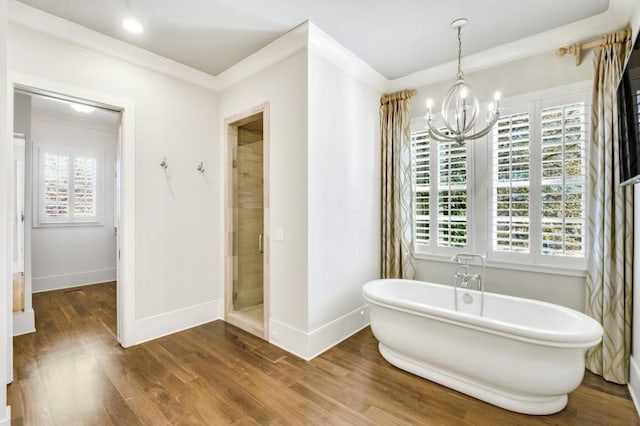 bathroom with a stall shower, baseboards, a soaking tub, ornamental molding, and wood finished floors