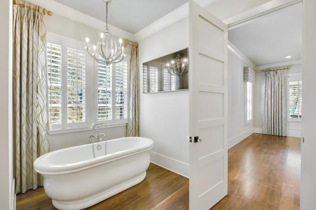 full bathroom with ornamental molding, wood finished floors, a freestanding tub, and baseboards