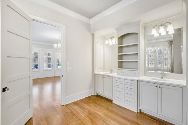 interior space with a chandelier, a sink, baseboards, light wood finished floors, and crown molding