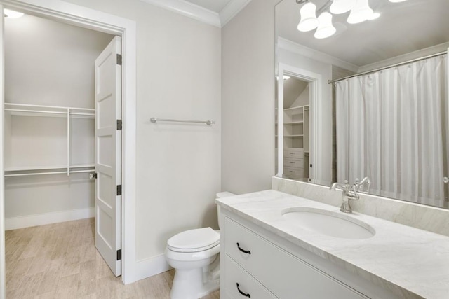 full bathroom with a walk in closet, ornamental molding, vanity, wood finished floors, and baseboards