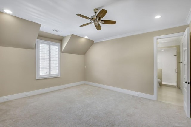 additional living space with lofted ceiling, light colored carpet, visible vents, a ceiling fan, and baseboards