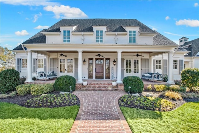 exterior space with a porch, a front yard, ceiling fan, and a shingled roof