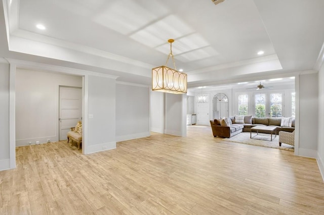 living room featuring crown molding, light wood finished floors, recessed lighting, a raised ceiling, and baseboards