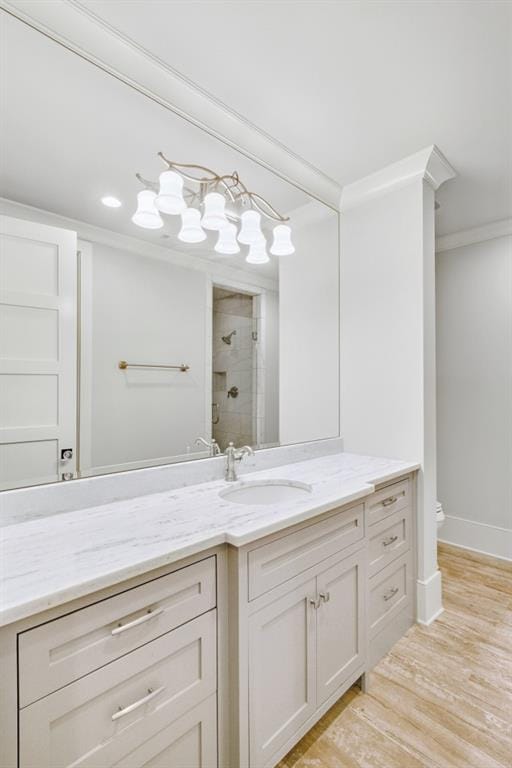 full bathroom featuring toilet, wood finished floors, vanity, tiled shower, and crown molding