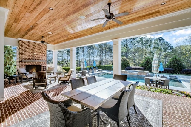 view of patio / terrace with ceiling fan, an outdoor brick fireplace, outdoor dining area, and a pool with connected hot tub