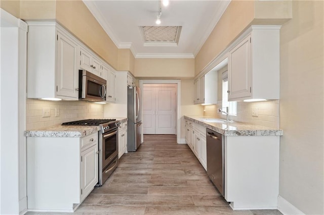 3636 Peachtree Rd NE Unit 405, Atlanta, GA 30319 - kitchen featuring appliances with stainless steel finishes, white cabinets, track lighting, light wood-type flooring, and ornamental molding