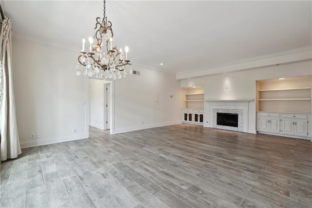 3636 Peachtree Rd NE Unit 405, Atlanta, GA 30319 - unfurnished living room with a chandelier, crown molding, built in shelves, wood finished floors, and a premium fireplace