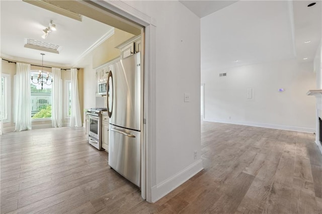 3636 Peachtree Rd NE Unit 405, Atlanta, GA 30319 - kitchen with stainless steel appliances, a chandelier, ornamental molding, wood finished floors, and pendant lighting