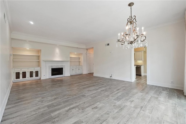 3636 Peachtree Rd NE Unit 405, Atlanta, GA 30319 - unfurnished living room with a chandelier, light wood finished floors, ornamental molding, built in features, and a high end fireplace