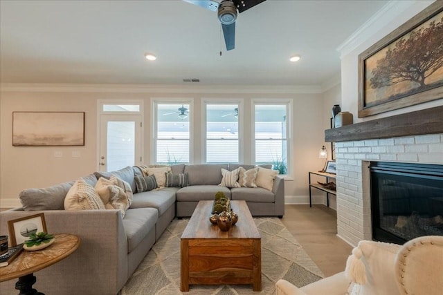 living room featuring ceiling fan, a fireplace, ornamental molding, and light hardwood / wood-style flooring