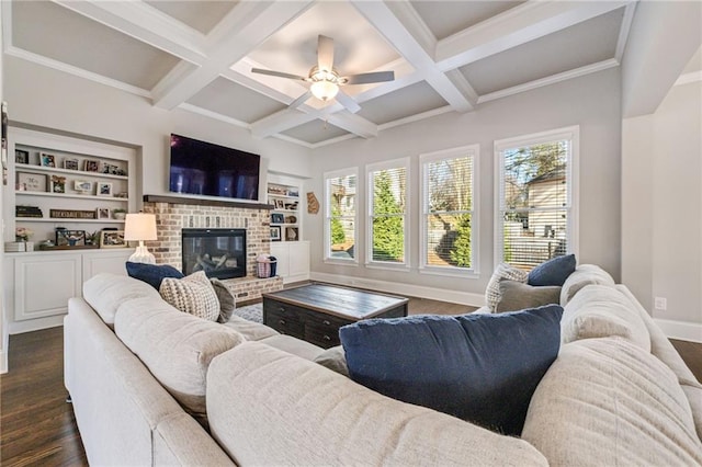 living room featuring dark wood-type flooring, built in shelves, ceiling fan, a fireplace, and beamed ceiling